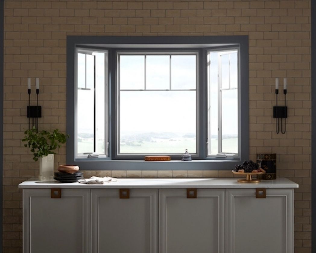 Gray kitchen bay window against brick wall