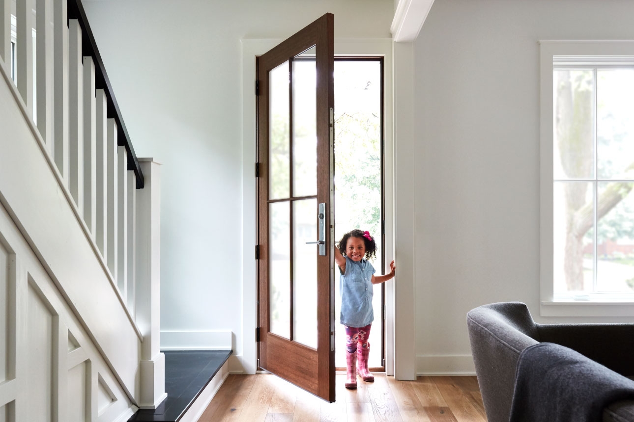 Girl entering home through front entry door with glass