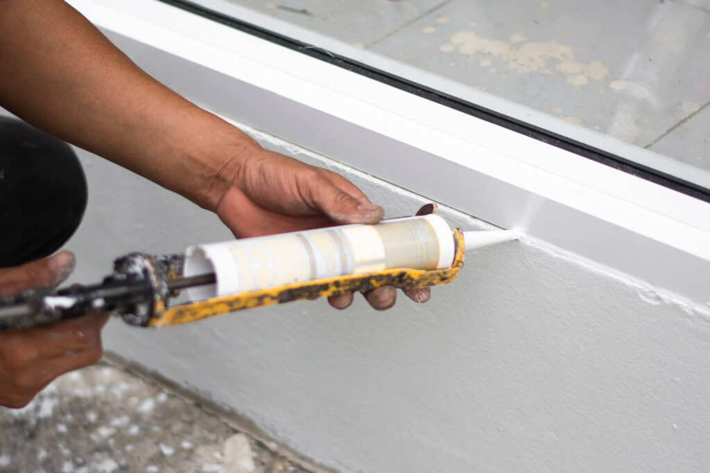 person applying caulk around window frame