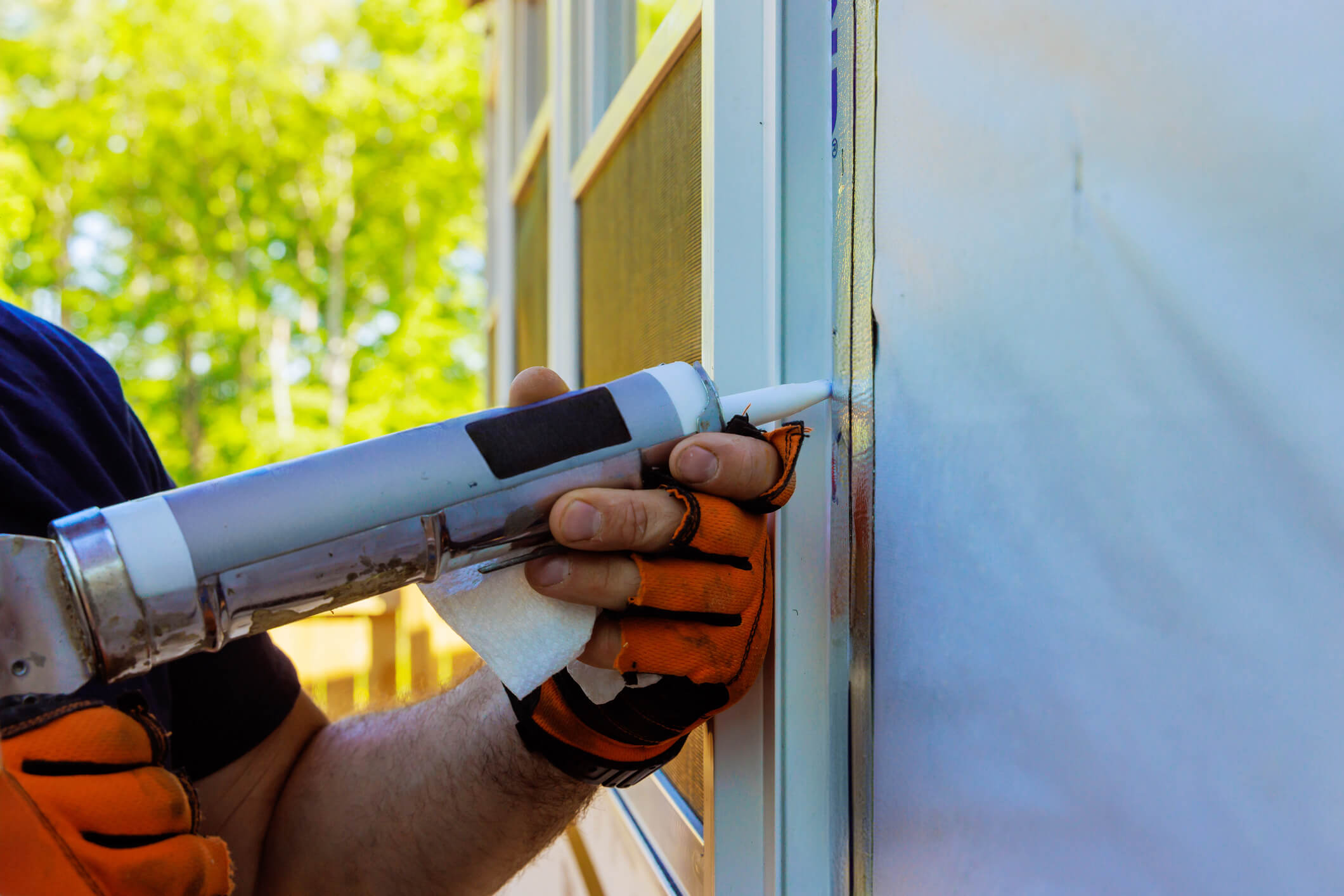 person applying caulk to outdoor window